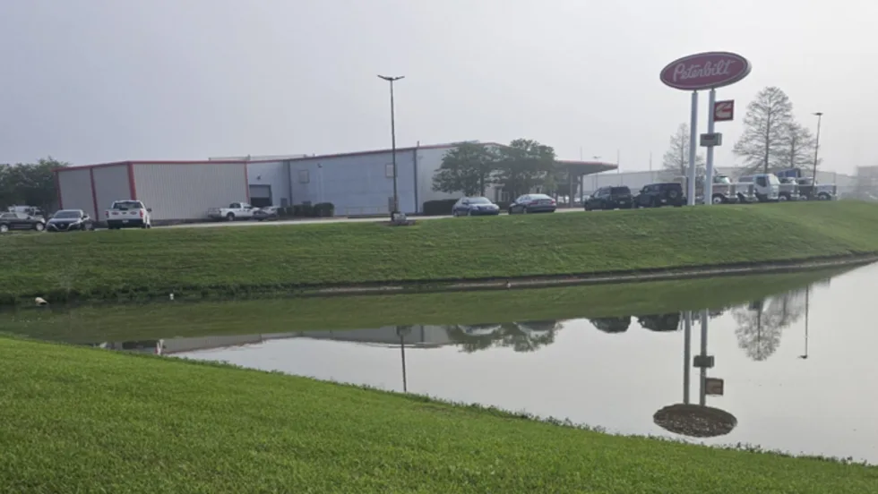Photo of truck dealership with pond in foreground 