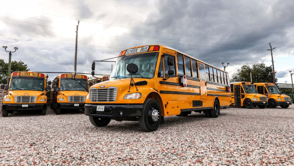 A line up of school buses with one out front of the group.