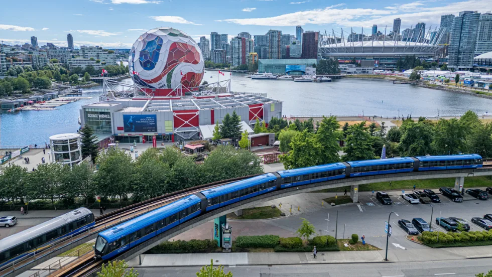 A TransLink train goes by a large FIFA World Cup soccer ball structure.