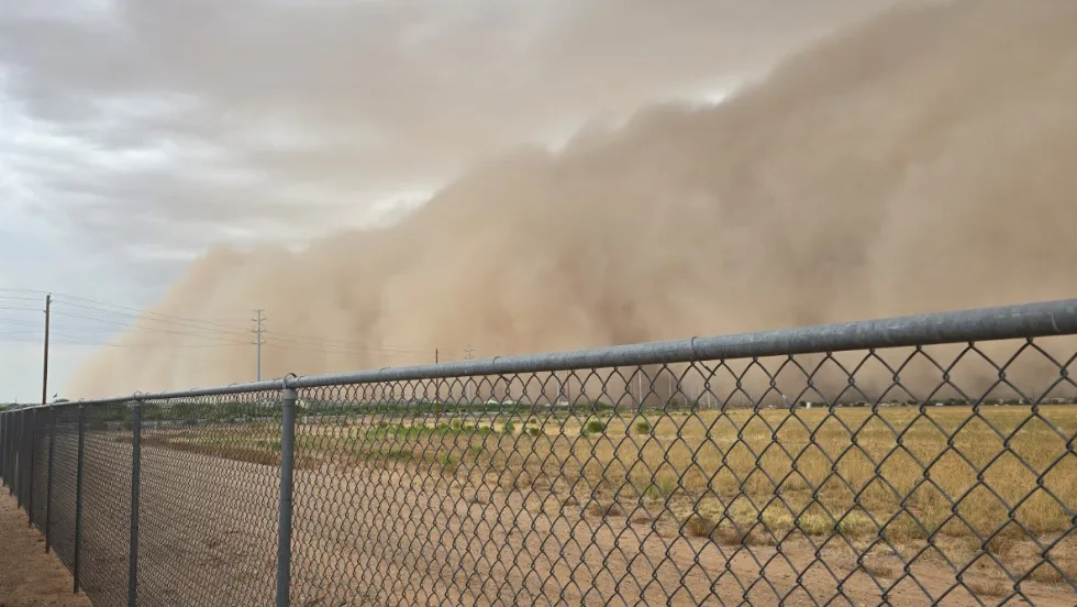 Large monsoon dust and rain wall moving across a field in Pinal County, Arizona, as severe weather brought flash flooding and hazardous driving conditions during school transportation operations.