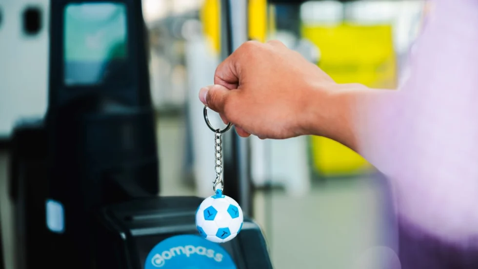 A person holding up a TransLink Compass Soccer Mini to a navigation terminal.