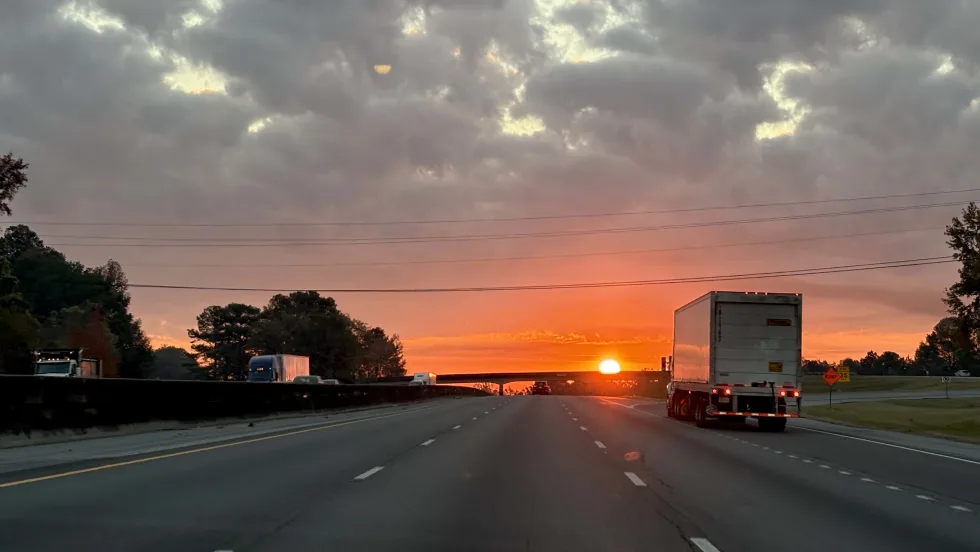 Truck on divided interstate highway driving toward sunrise