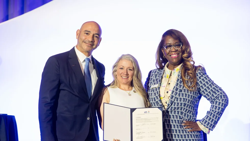 Three people pose for a picture with a signed document.