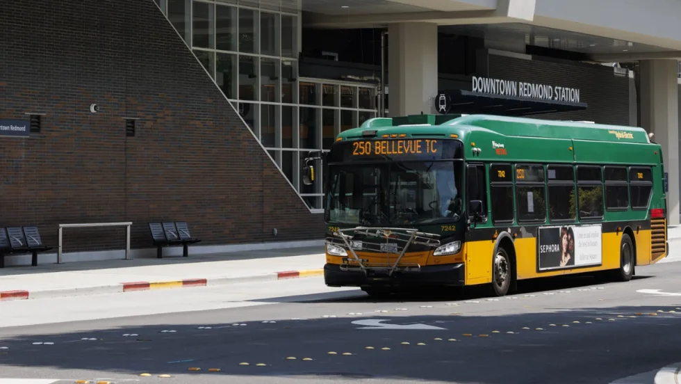 A green and yellow King County Metro bus outside a station.