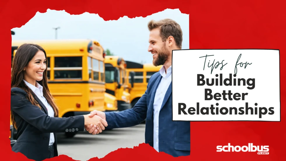  An image of a woman and a man, both dressed in professional attire, shaking hands in a school bus dealership lot surrounded by various buses.