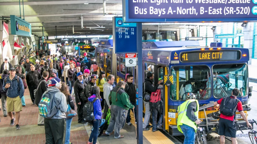 Riders getting on buses at a station.