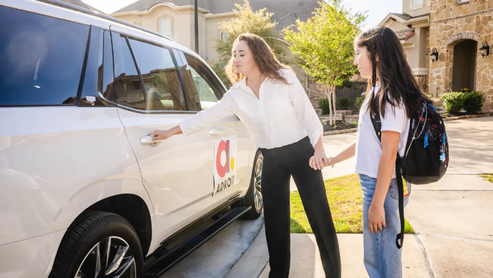 An Adroit driver opening a car door for a student.