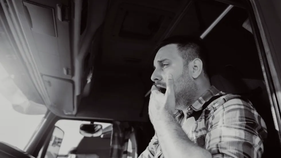 Truck driver yawning behind wheel