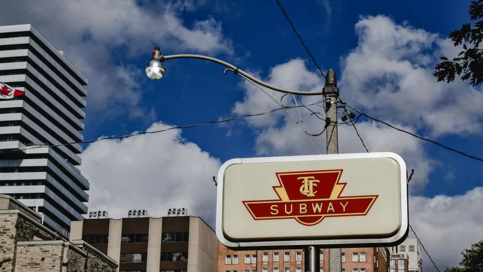 A vintage TTC sign against a blue cloudy sky.