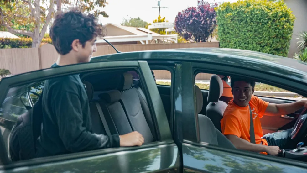 A young male student gets into the backseat of a HopSkipDrive CareDriver vehicle.