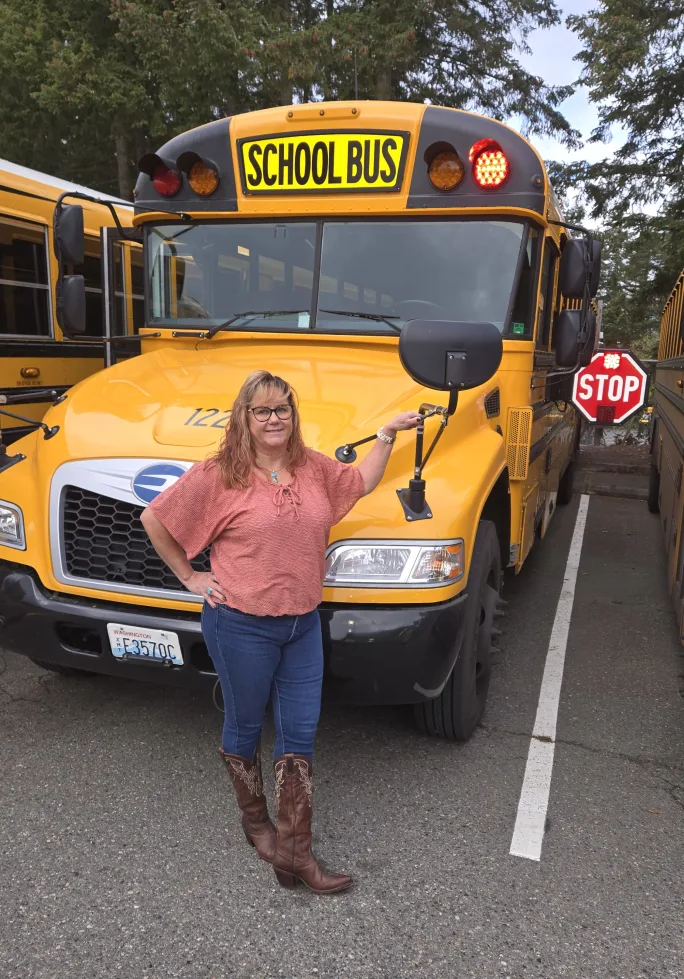Dawnett Wright poses in front of a parked school bus with its stop arm extended.