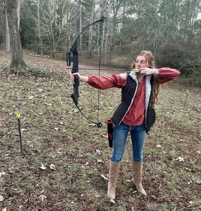 Young woman with compound bow and arrow