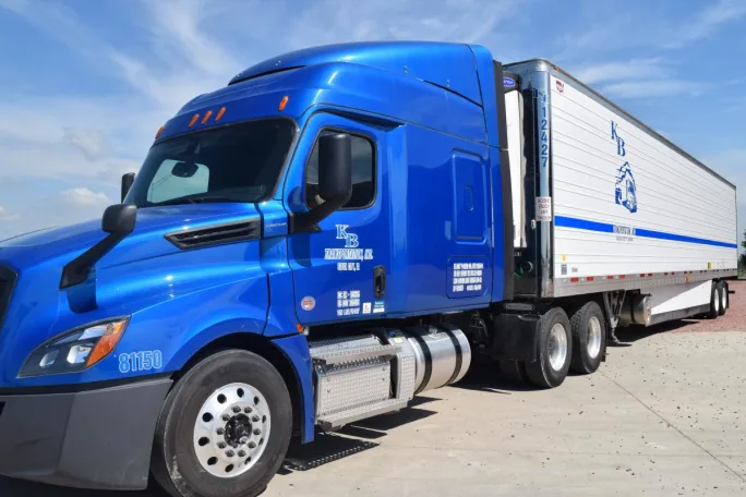 Blue heavy-duty truck pulling a refrigerated trailer.