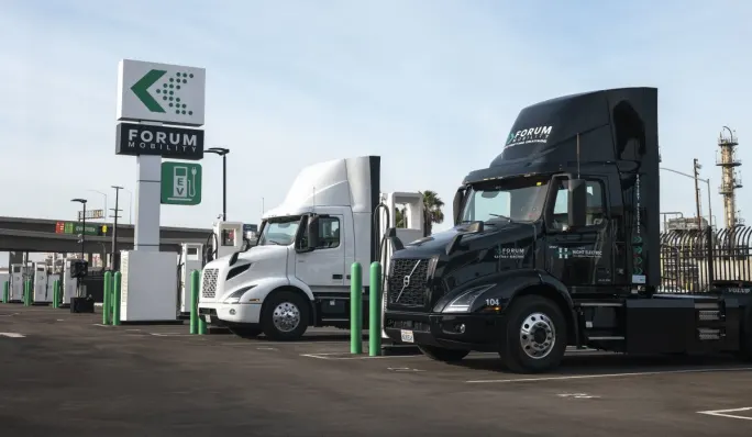 Two Volvo electric trucks at a Forum Mobility charging depot