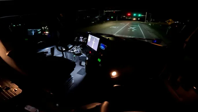 View from inside autonomous truck cab at night at stoplight