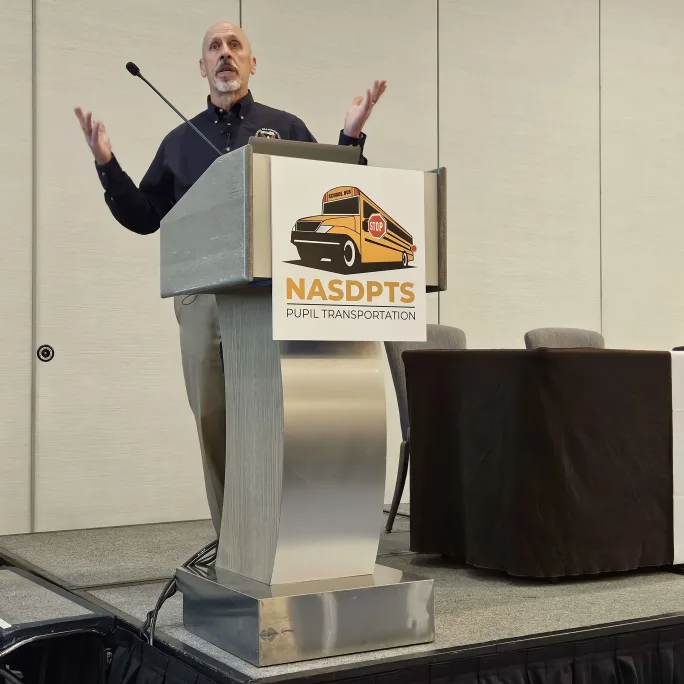 michael graham stands at a podium with a NASDPTS logo on the front