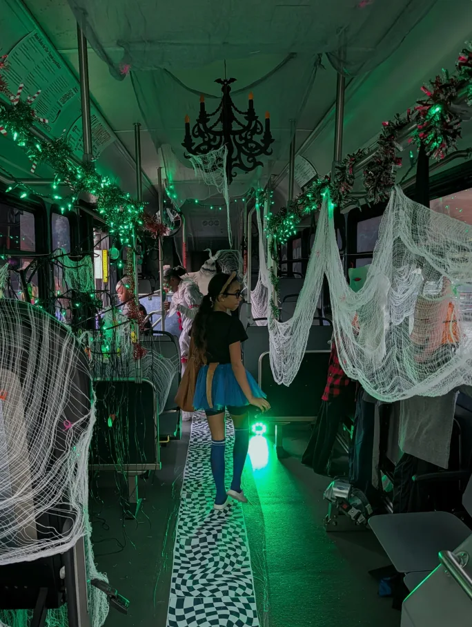 Attendees walk through METRO RTA’s Halloween-themed Boo Bus, decorated with green lights, cobwebs, garlands, and other spooky decorations.