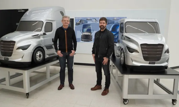 Two Freightliner design team members stand beside scale models of the fifth-generation Cascadia inside a design studio.