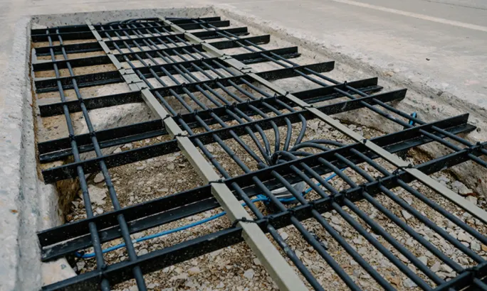 Close-up of wireless charging transmitter coils embedded beneath a section of concrete roadway.