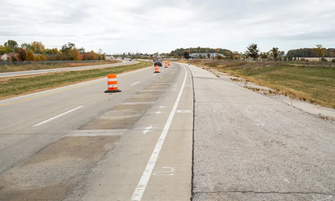Modified highway lane with construction barrels marking a test section used for wireless charging research.