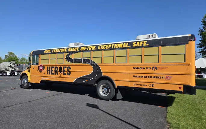 Krise Transportation school bus featuring American Student Transportation Partners’ “Heroes” school bus driver mobile studio, with “Here. Everyday. Ready. On-Time. Exceptional. Safe.” displayed along the roofline.
