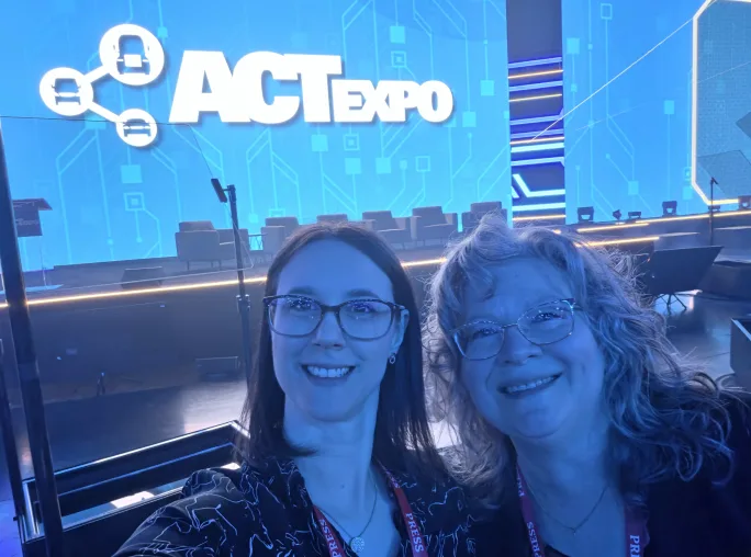 two women take a selfie in front of the ACT expo stage