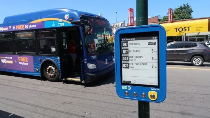A New York MTA bus with an Axentia passenger information sign in the foreground.