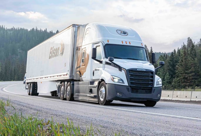 Photo of Bison Transport truck on a highway with evergreen forest in the background