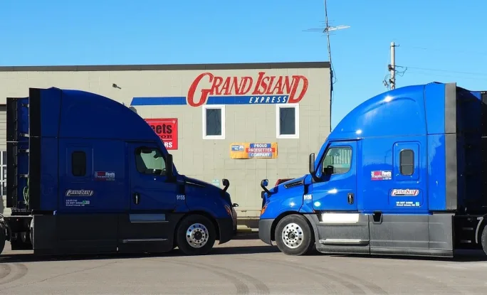 Two trucks parked head to head in front of Grand Island Express building