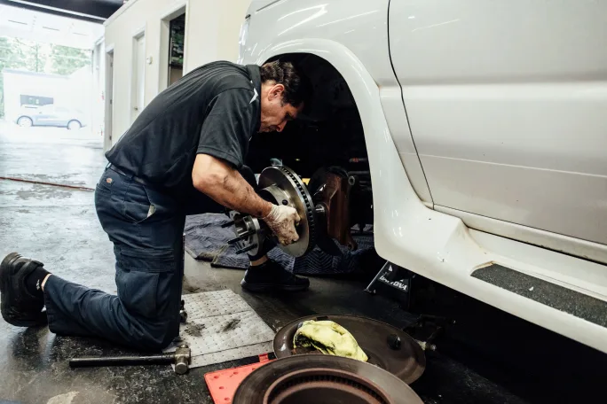 A mechanic working on shuttle bus brake system.