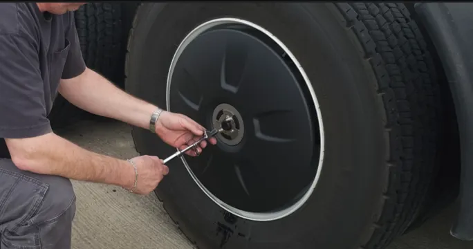 Truck tire with aero wheel cover with technician checking air pressure