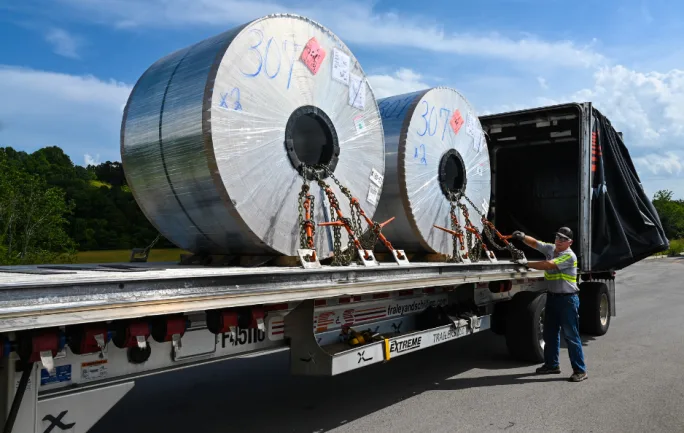 Photo of driver securing load of coils on a flatbed trailer