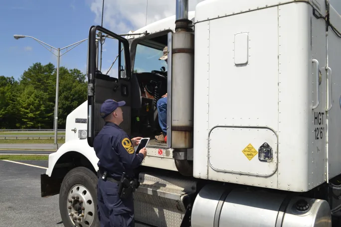 Truck with driver's door open with commercial motor vehicle inspector talking to driver