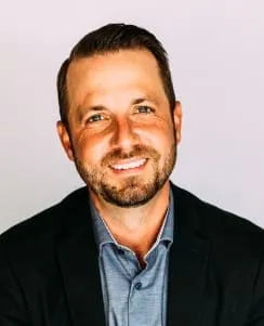 Headshot of male with beard in a suit jacket with open collar shirt