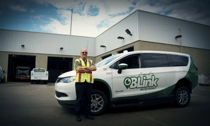A Bloomington Transit BLink driver posing with a BLink vehicle.
