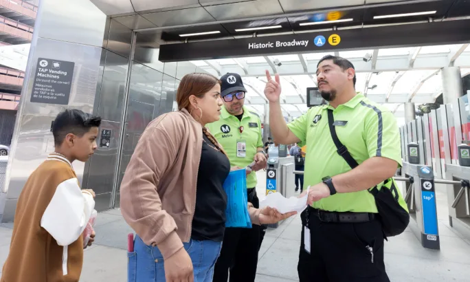 A woman and young boy talk to two Los Angeles Metro Ambassadors.