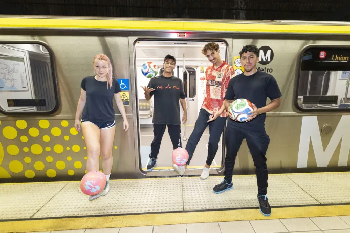 Young soccer players posing in front of an LA Metro railcar