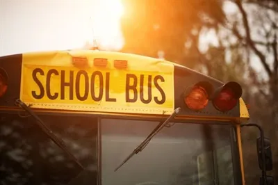 the top of a school bus is illuminated by a rising sun behind it