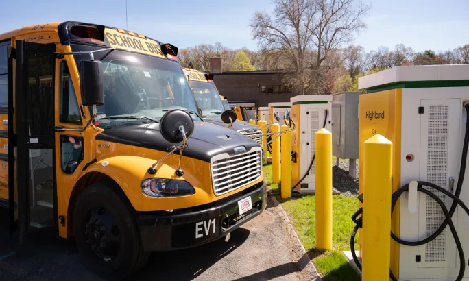 An electric school bus near Highland Electric Fleet branded charging infrastructure.