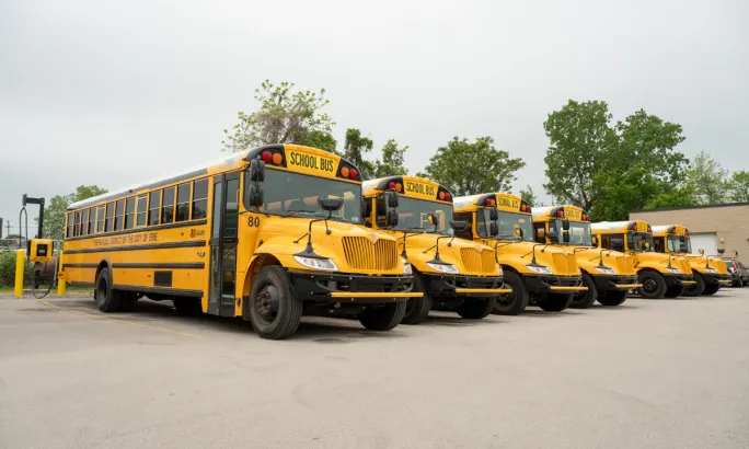 A lineup of electric school buses parked outside.