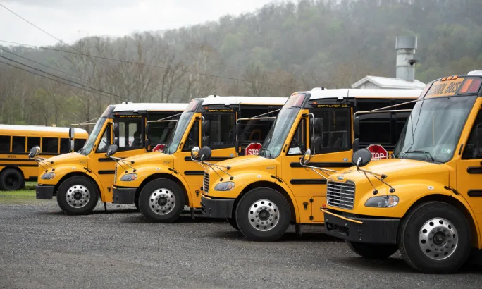 A lineup of electric school buses parked outside.