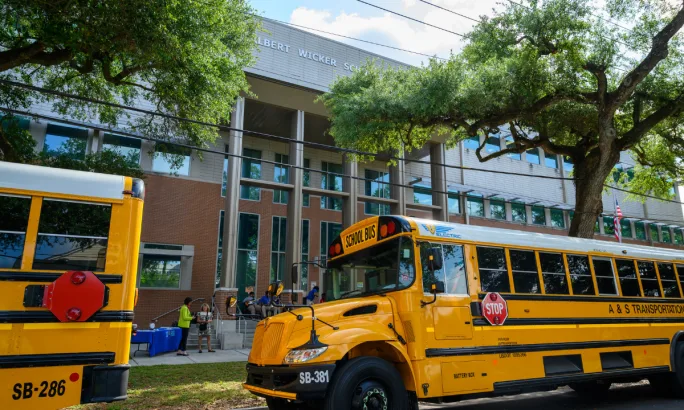 Electric IC Buses parked outside of a school building.