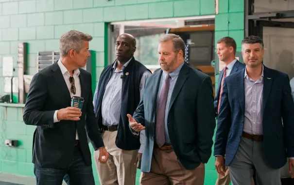 U.S. Transportation Secretary Sean Duffy speaks with NSTA President Patrick Dean during a visit to Dean Transportation in Lansing, Michigan, as other attendees walk alongside them.