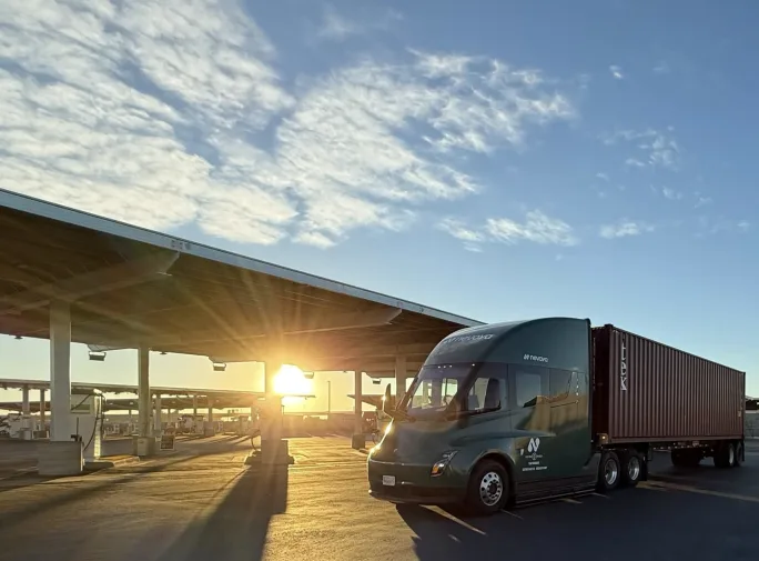 Photo of electric truck at charging station with sunrise