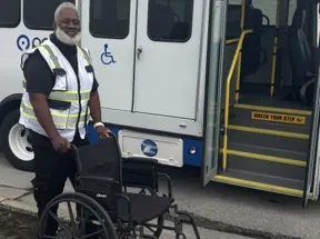 WeDriveU Road Supervisor Charles Herring stands beside a wheelchair in front of a Pace paratransit vehicle in South Cook County, Illinois.