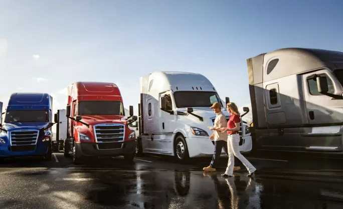 Man and woman walking in front of a line of used heavy duty trucks