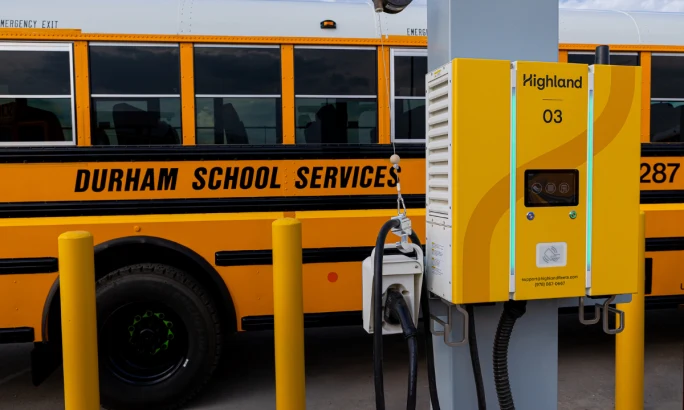 A Durham School Services bus next to a Highland charger.