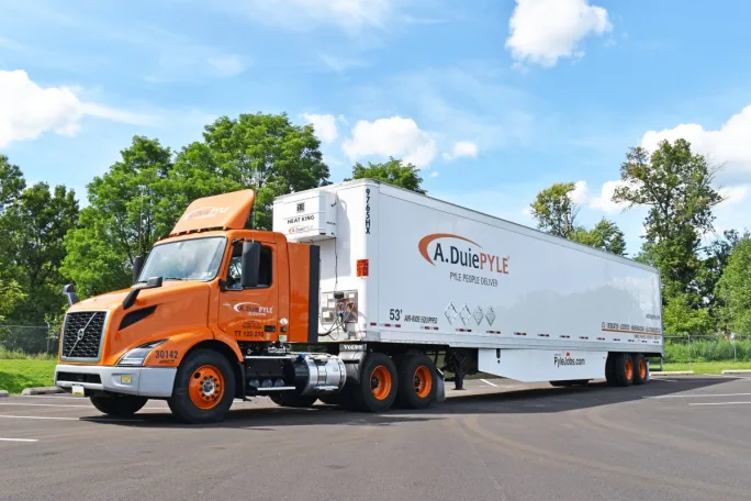Orange truck tractor pulling A. Duie Pyle trailer