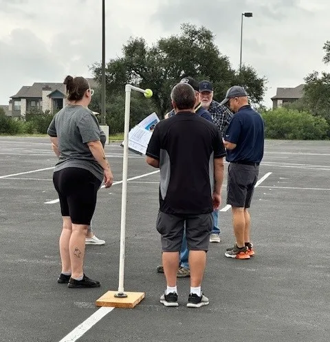 STA training attendees stand next to a stanchion in a parking lot.