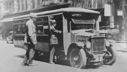 Historical black and white photograph of A.J. Ferraro boarding one of the first makeshift buses.